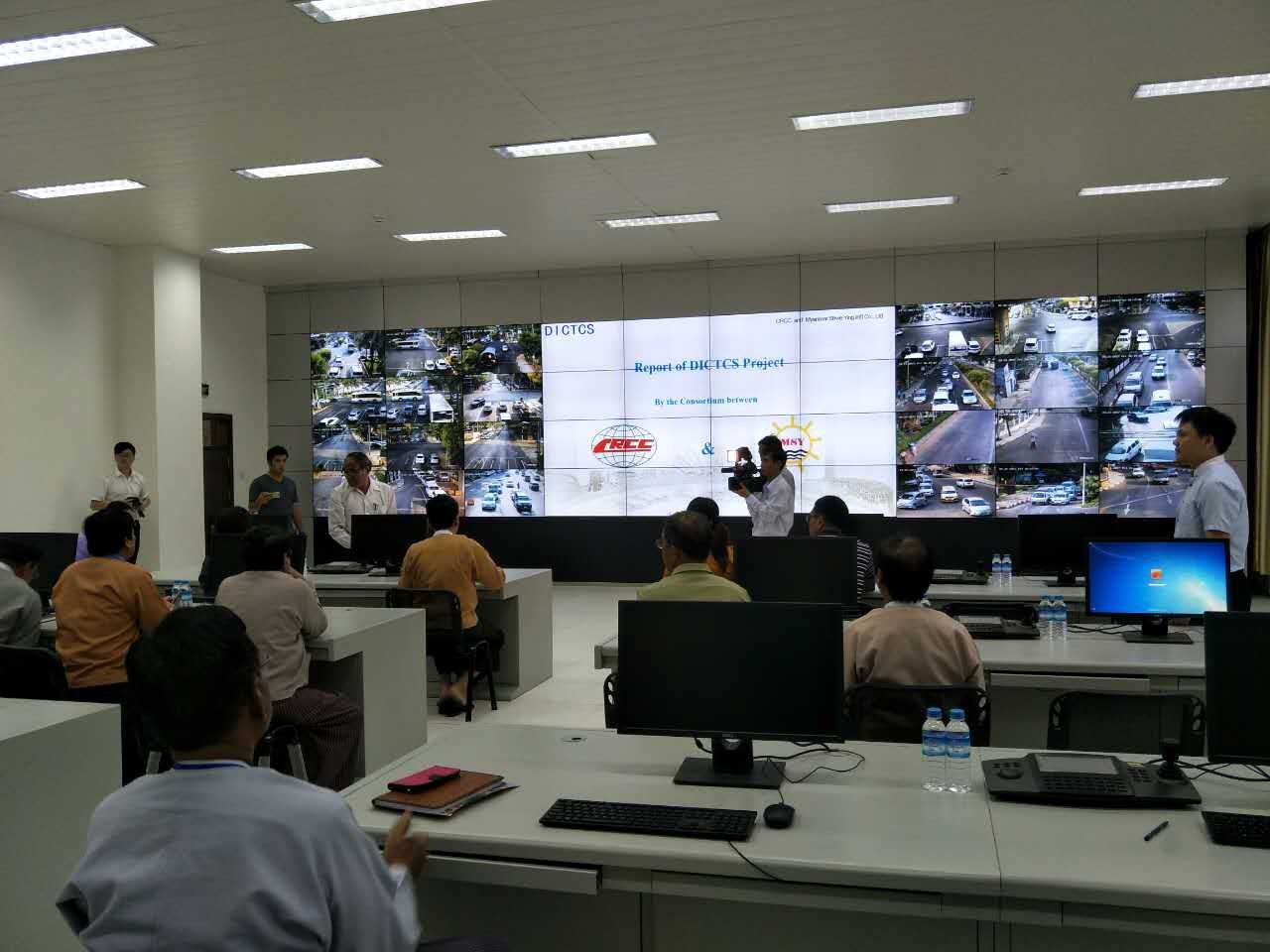 Operators in a traffic control room facing a wall of live road cameras