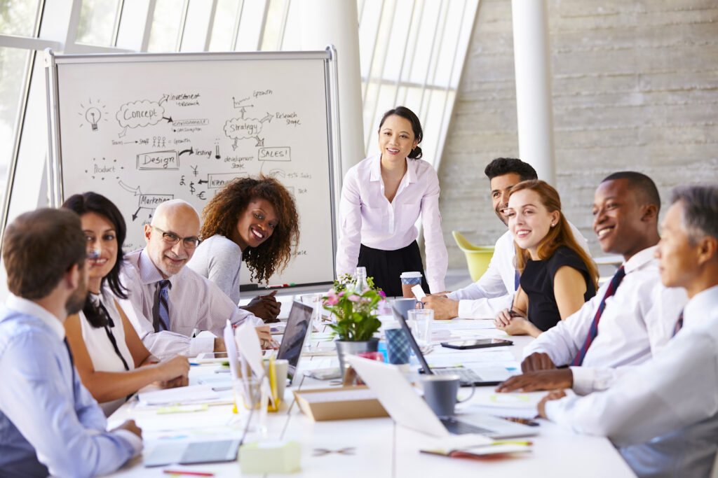 A team around a conference table beside a whiteboard of business plans